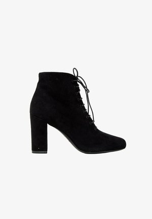 Bottine noire en daim avec talon haut et épais et lacets à l'avant, vue de profil sur fond blanc.