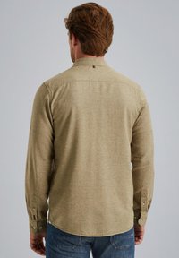 Khaki dlouhá košile s jemnou texturou, špičatým límečkem a knoflíkovými manžetami. Obsahuje zadní sedlo a logo blízko límce.