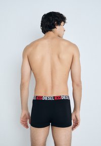 Black boxer shorts with a Diesel logo waistband. The fabric appears smooth and fitted, showcasing a simple design with no visible patterns.