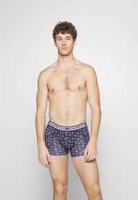 Navyfarbene Boxerbriefs mit einem floralen Muster, ausgestattet mit einem weißen Bündchen, das "JACK & JONES" beschriftet ist. Hergestellt aus dehnbarem Stoff für zusätzlichen Komfort.