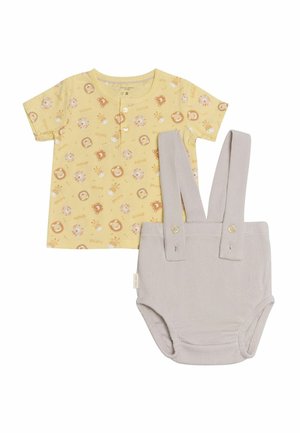 Camiseta de algodón amarilla con estampado de animales y botones en el frente, combinada con pantalones cortos grises acanalados con tirantes y detalles de botones.