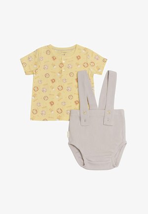 Camiseta de algodón amarilla con estampado de animales y botones en el frente, combinada con pantalones cortos grises acanalados con tirantes y detalles de botones.