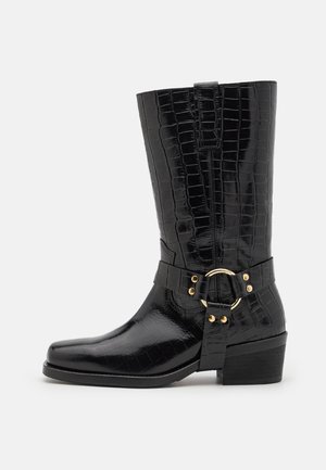Czarne kozaki do kolan z fakturą skóry krokodyla, kwadratowym noskiem, złotymi ozdobami i kształtowanym obcasem.
