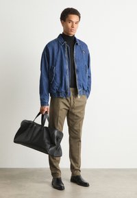 Denim bomberska jakna, temno modra; črna turtleneck majica; svetlo rjave hlače; črna usnjena torba s smooth teksturo; črne čevlje.