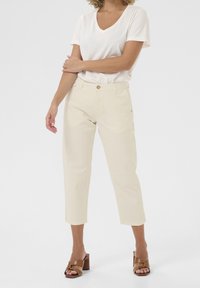 Beżowe, krótkie spodnie o prostym kroju; wykonane z bawełny o gładkiej teksturze; z przodu z guzikiem i zamkiem błyskawicznym, w zestawie z białą koszulą z dekoltem w serek.