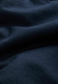 Tissu bleu marine foncé avec des plis doux et une surface légèrement texturée, présenté en gros plan.