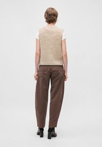 Bežna pletena brezrokavnica z teksturiranim zaključkom, nosita jo over belim srajcem. Rjav baggy hlače in črne čeveljčke s peto dopolnjujejo videz.