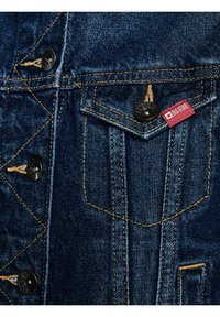 Tumesinine teksajaki tasku oranži õmblusega, metallist nööbid kirjaga "BIG STAR" ning punane kangast silt tähelogoga.