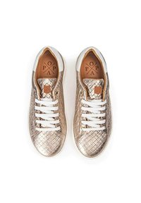 Zapatillas metálicas doradas con una textura trenzada, cordones blancos y un detalle en el talón blanco. Cuenta con una plantilla marrón con detalles del logo.