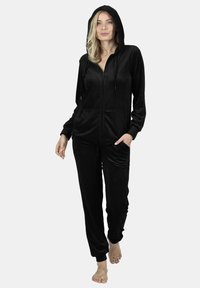 Black hooded tracksuit made of soft fabric. Features zip-up front, two front pockets, and fitted cuffs. Sleek design with a smooth texture.