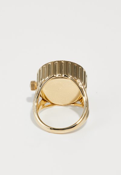 Goldring mit einem gerippten Band und einer glatten, kreisförmigen Fläche. Die Unterseite zeigt eine strukturierte Oberfläche und einen kleinen seitlichen Knopf.