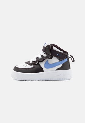 Hoge zwart-witte sneaker met een blauwe Nike-swoosh, witte veters en een witte zool, vanaf de zijkant getoond op een effen achtergrond.
