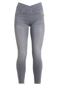 Jeans skinny de denim gris con una cinturilla cruzada y bolsillos frontales. La tela tiene una textura suave con un acabado de lavado medio.