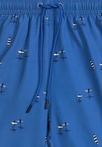 Niebieskie kąpielówki wykonane z lekkiego materiału, z elastycznym pasem na sznurku, zdobione powtarzającym się wzorem surferów i desek surfingowych.