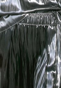 Glinsterende zwarte geplooide stof met een soepele, reflecterende textuur; beschikt over een elastische tailleband en vloeiende draperingen.