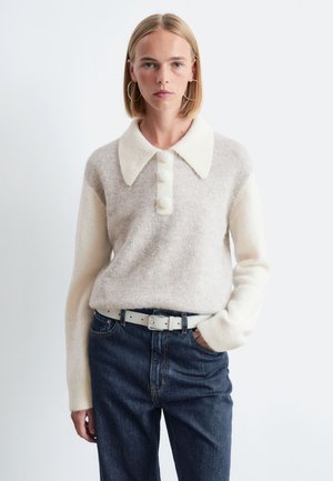 Beige knit sweater with a white collar, featuring three buttons and long sleeves. Paired with dark blue jeans and a light belt.