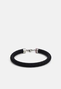Bracciale in pelle intrecciata nera con hardware in argento. Presenta un gancio a moschettone e un accento rosso, bianco e blu vicino alla chiusura.