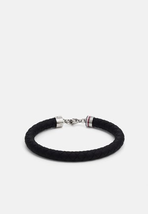 Black braided leather bracelet with silver hardware. Features a lobster clasp and a red, white, and blue accent near the closure.