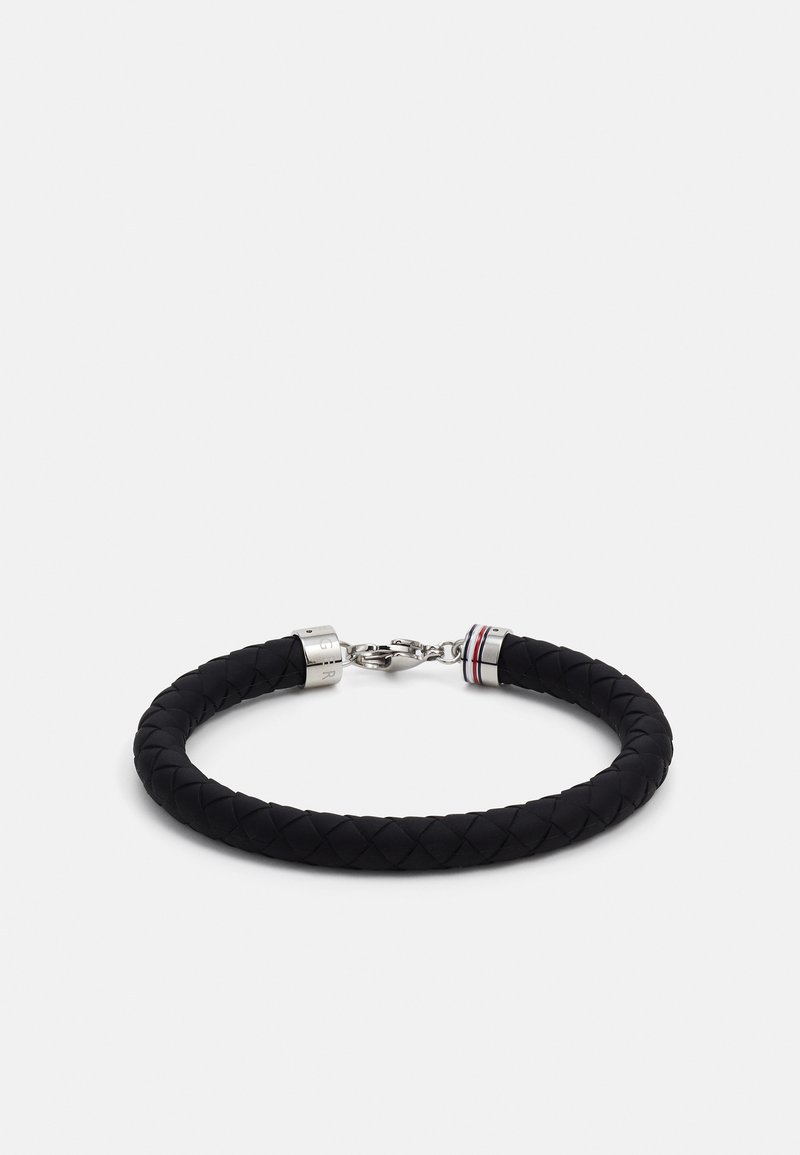 Bracciale in pelle intrecciata nera con hardware in argento. Presenta un gancio a moschettone e un accento rosso, bianco e blu vicino alla chiusura.
