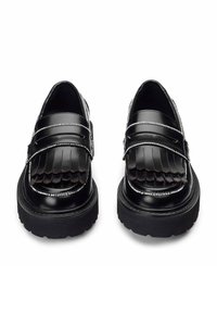 Mocassini neri in pelle con dettagli frangiati, accenti in argento e suole in gomma spesse. Il design presenta una forma della punta elegante e arrotondata.