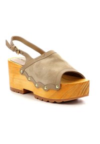 Sandalo a zoccolo in suede nocciola con piattaforma in legno, bordo scallop, borchie dorate e cinturino alla caviglia regolabile. Base in legno texturizzato con battistrada a zigzag.