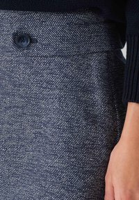 Een marineblauwe op maat gemaakte rok van gestructureerde stof, met een sluiting aan de voorkant van knopen en een gladde tailleband.