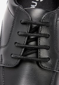 Chaussure en cuir noir avec une finition lisse, six œillets avec des lacets noirs et des coutures renforcées le long des seams. Design classique.