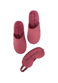 Różowe kapcie w paski o gładkiej fakturze. Dopasowana opaska na oczy do spania z elastycznym paskiem i napisem „późne wymeldowanie”. Miękki i wygodny design.