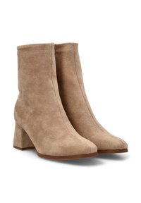 Botines de ante beige con tacón cuadrado, que presentan un diseño elegante y punta redonda. La textura es suave y lisa.