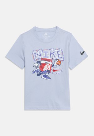 T-shirt Nike bleu clair avec un carton de lait rouge en dessin animé dribblant un ballon de basket, texte « NIKE » stylisé au-dessus et swoosh Nike noir sur la manche gauche.