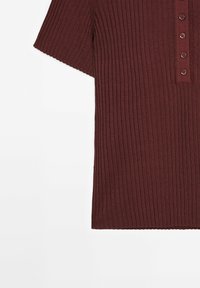 Burgundy ribbad stickad topp med korta ärmar, med en femknapps placket och rak fåll. Texturerad tyg med vertikala ränder.