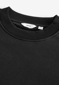 Zwarte sweatshirt met een geribbelde ronde hals, een geborstelde binnenkant en een label met de maat en herkomst. Gestructureerde stof met een gladde buitenkant.