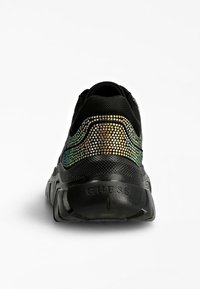 Schwarzer Sneaker mit dicker Sohle, ausgestattet mit schimmernden Strasssteinen am Rücken und "GUESS" geprägt an der Ferse.