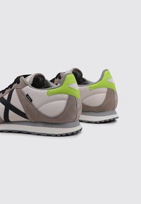 Sneakers with a mix of light gray leather and suede, black accents, a bright green heel tab, and a textured rubber sole.
