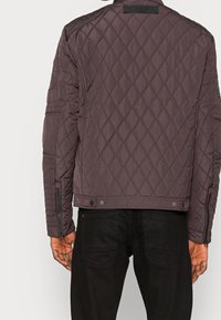 Giacca trapuntata grigio scuro in stile bomber, con una texture liscia, cerniere sulle maniche e chiusure a pressione in vita.