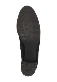 Chaussure en suede noir avec une semelle en caoutchouc texturé présentant un motif de crampons, un bout rond et des accents élastiques sur les côtés pour un ajustement optimal.