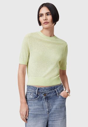 Kortærmet, lysegrøn striktrøje med rund halsudskæring, der har ribkant ved kanten og ærmerne, parret med højtaljede, ødelagte denimshorts.