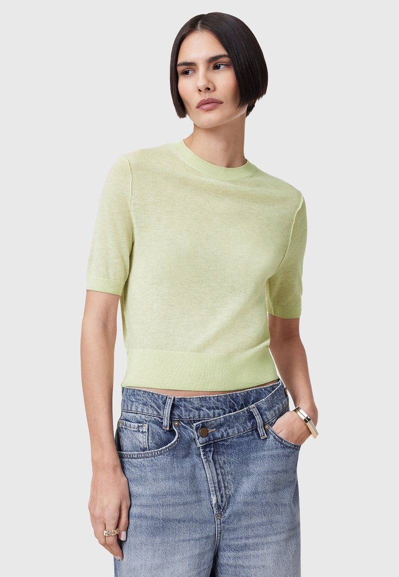 Korte mouwen, lichtgroene gebreide trui met een ronde hals, met een geribde zoom en manchetten, gecombineerd met high-waisted verwarde denim shorts.