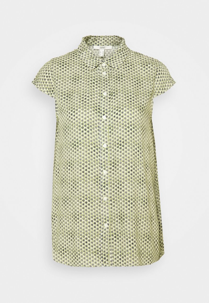 Blouse manches courtes vert clair avec petits motifs géométriques foncés et boutons sur le devant, avec un col et une coupe ample.