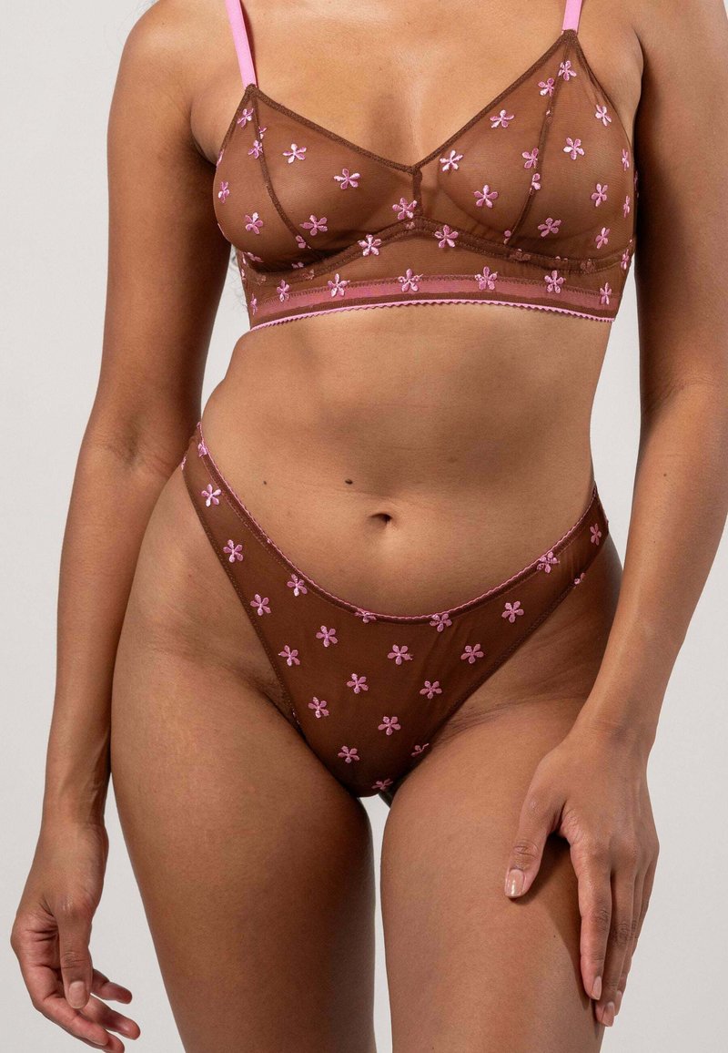Bruine doorschijnende lingerieset met roze bloemenborduursel, bestaande uit een bralette en bijpassende bikinibroekjes, met delicate stiksels en zacht materiaal.