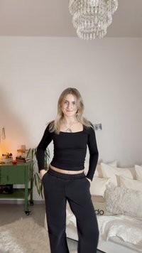 Top preto de manga comprida com decote quadrado, combinado com calças de jogging pretas de corte relaxado. Tecido liso e cintura elástica, design minimalista.