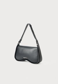 Bolsa de ombro de couro preto com borda inferior curvada e alça ajustável, apresentando um pequeno detalhe em logotipo prateado na frente.