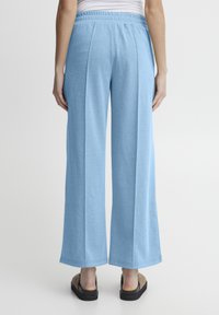 Lichtblauwe wijde broek in een zachte, gestructureerde stof; heeft een elastische tailleband en zijplooien voor extra ontwerpdetails.