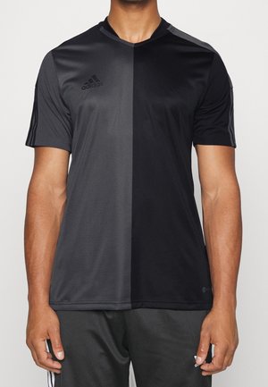 Mann trägt ein kurzärmeliges Adidas-Sportshirt mit einem vertikalen Design in Dunkelgrau und Schwarz.