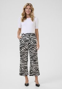 Fekete-fehér zebra mintás, széles szárú nadrág, elasztikus derékkal és oldalsó zsebekkel, illeszkedő fehér rövid ujjú toppal párosítva.