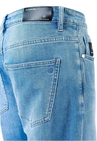 Šviesiai mėlynos spalvos džinsai iš džinso audinio su penkiomis kišenėmis, gale odinis prekės ženklo ženklas ir siuvimo detalės ant kišenių.