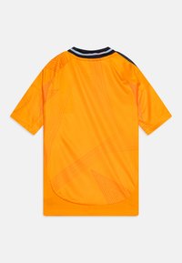 Maillot de sport orange avec un col rond noir et blanc, des manches courtes et des motifs géométriques subtils sur le tissu.