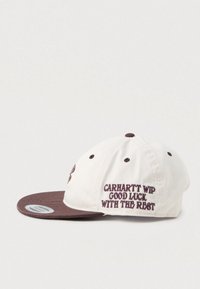 Casquette de baseball crème et marron avec le texte brodé "Carhartt WIP Bonne chance pour la suite" sur le panneau latéral.