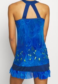 Modré sportovní šaty s texturovaným květinovým vzorem, designem na závodní záda a volánovým lemem. Obsahuje kontrastní odstíny modré a zelené.