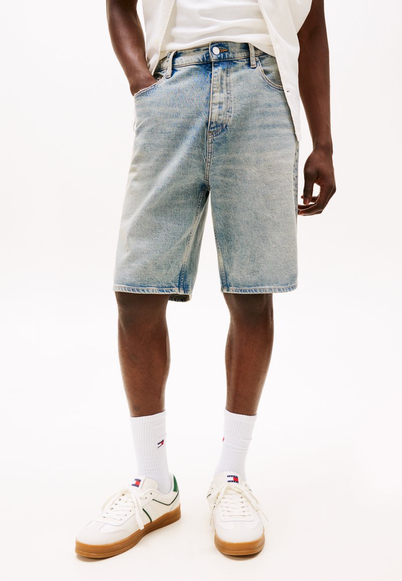 Light blue denim shorts feature a relaxed fit, five-pocket design, and contrast stitching. Paired with white sneakers and ribbed socks.